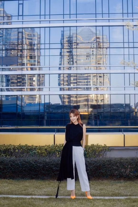Triệu Vy chọn cho mình set đồ đen-trắng tinh tế với áo vạt dài mix cùng quần culottes lửng trắng tô điểm cùng đôi cao gót màu cam neon nổi bật