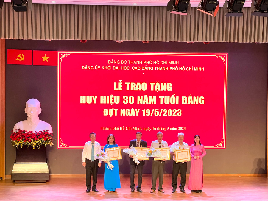 Bà Nguyễn Thị Là, Phó Bí thư Thường trực Đảng ủy Khối Đại học, Cao đẳng TPHCM (bìa phải) trao tặng Huy hiệu 30 năm tuổi Đảng cho các đảng viên. 