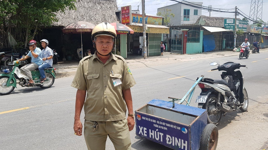 Ông Nguyễn Văn Hồng đang đi thu gom đinh bị rải trên đường.