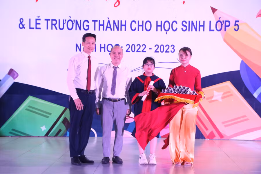 Thầy Nguyễn Duy Khuê (bìa trái) - Hiệu trưởng Trường Tiểu học Times School trao giấy chứng nhận hoàn thành chương trình tiểu học cho đại diện học sinh và phụ huynh khối 5 của trường.
