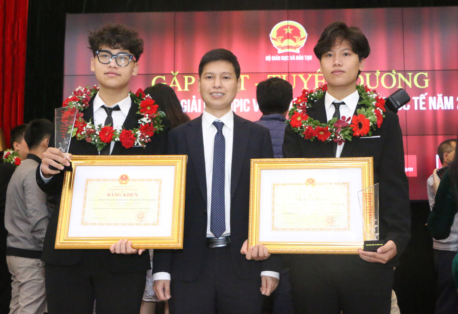 Thầy Trần Văn Huy chúc mừng thành tích của hai em Phạm Nguyễn Quang Huy (trái) và Phạm Nguyễn Gia Bảo.