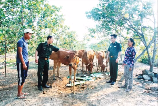 Cán bộ Đồn Biên phòng cửa khẩu Lộc Thịnh thăm gia đình được đơn vị tặng bò giống. Ảnh: Văn Hoàn