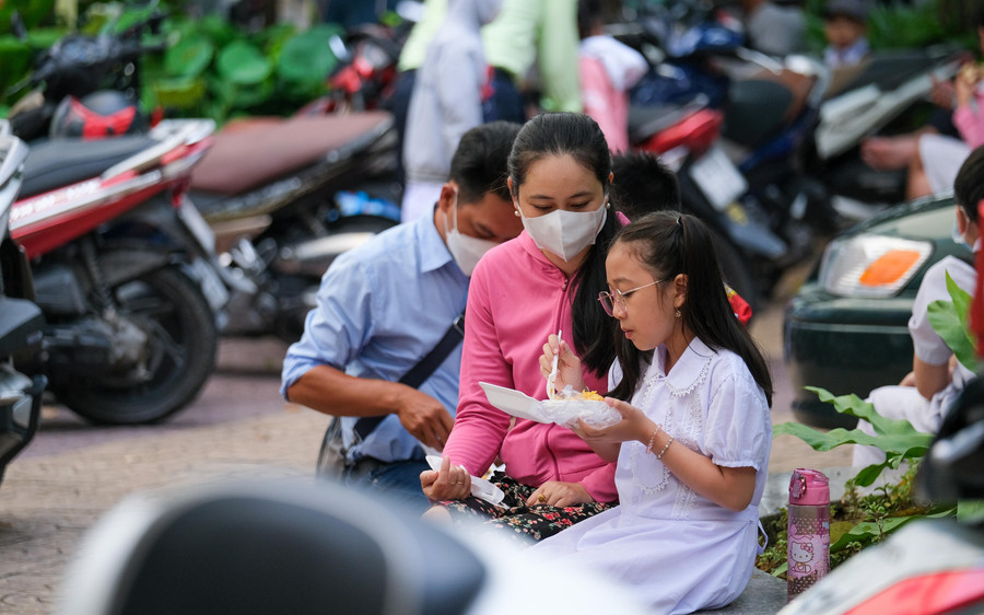 Phụ huynh tranh thủ thời gian cho con ăn sáng tại sân trường.