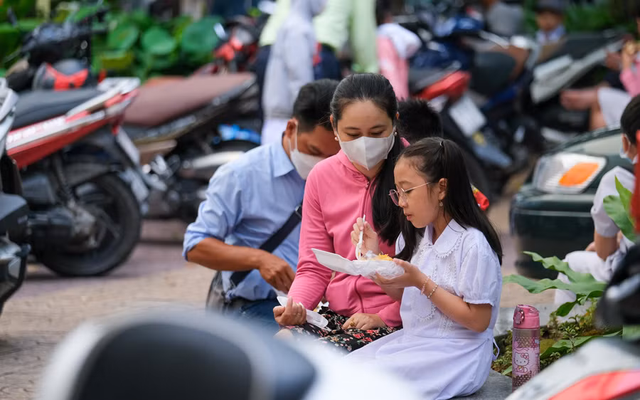 Phụ huynh tranh thủ thời gian cho con ăn sáng tại sân trường.