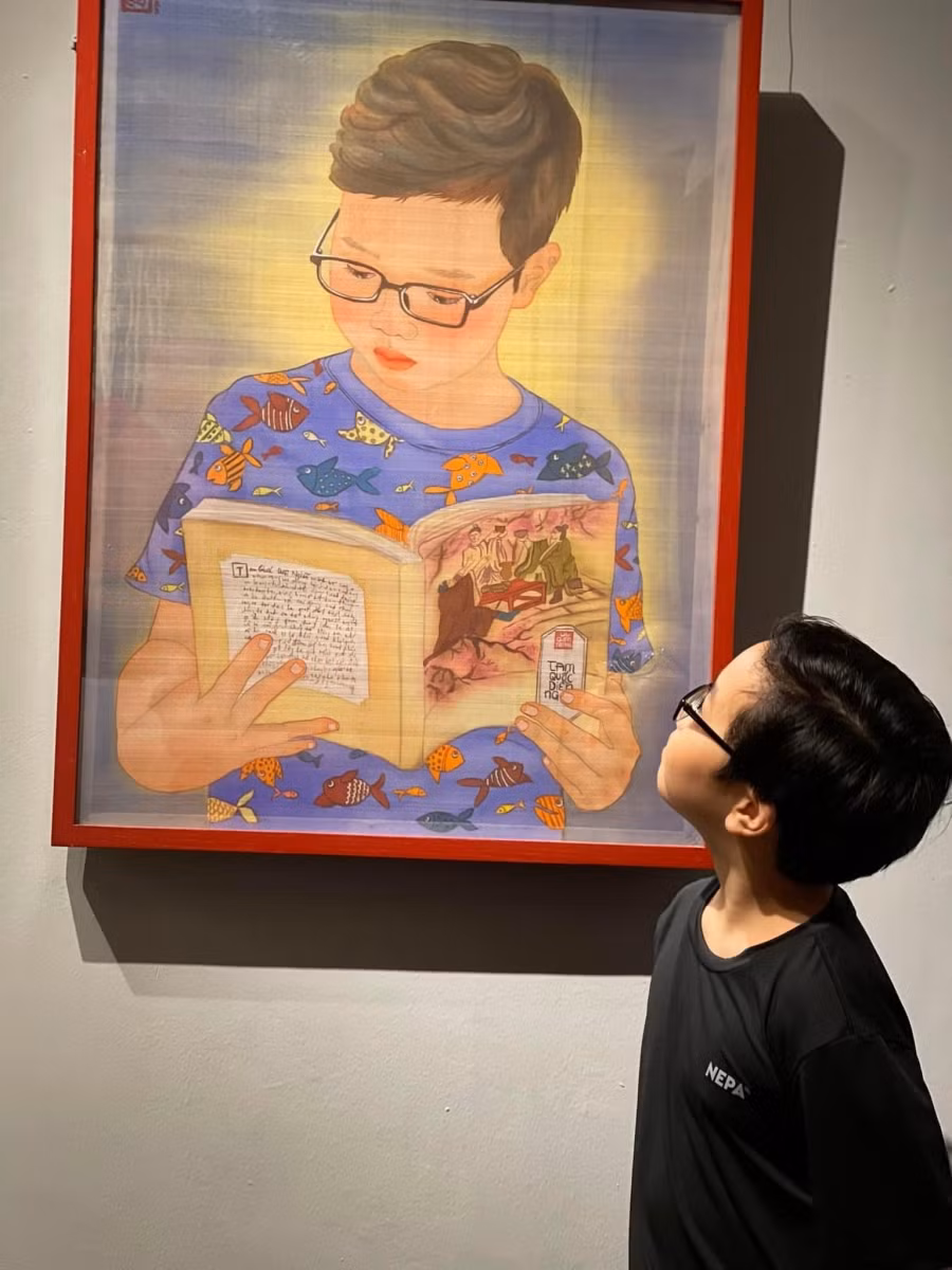 Nhân vật đọc sách xem tranh vẽ mình.