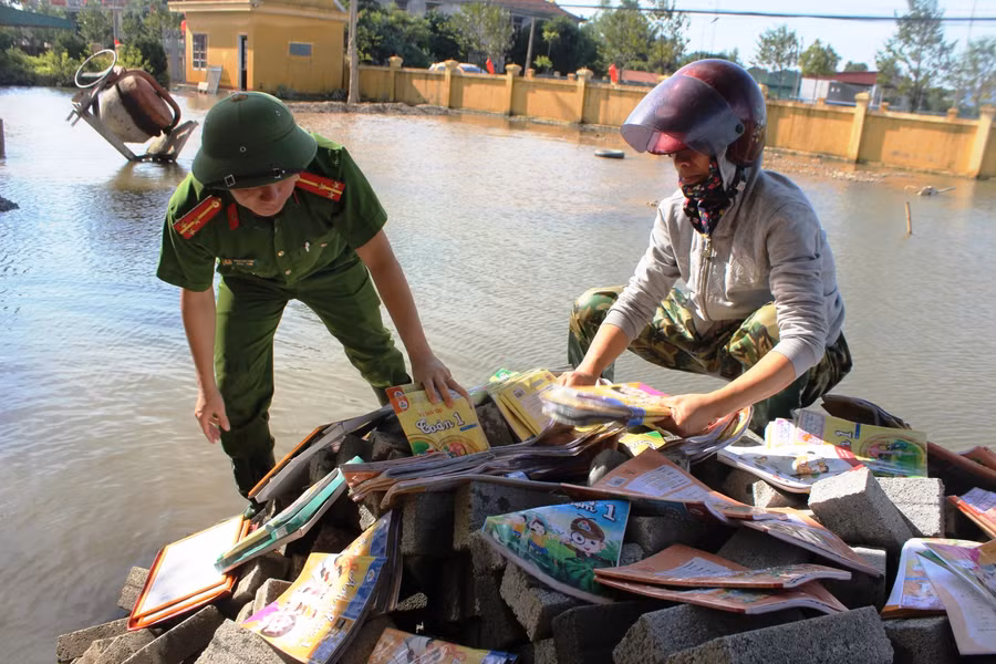 Công an huyện Thạch Hà (Hà Tĩnh) cùng giáo viên thu gom sách vở của HS sau lũ.