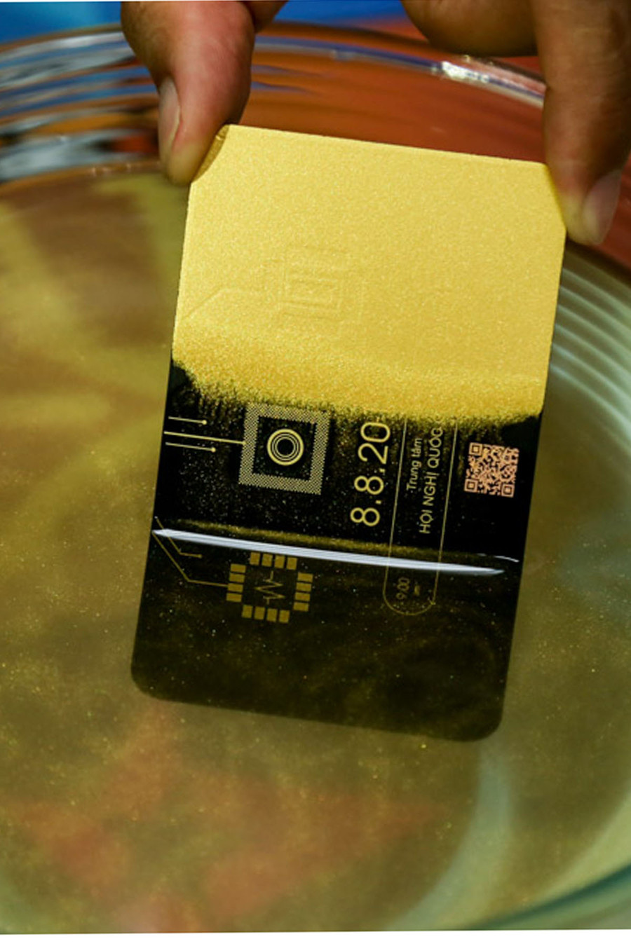 Mặt sau tấm thiệp khi nhúng vào nước lớp mạ vàng dần biến mất và để lộ thông tin về sự kiện lúc 9h ngày 8/8/2017 tại Trung tâm Hội nghị Quốc gia – Hà Nội.