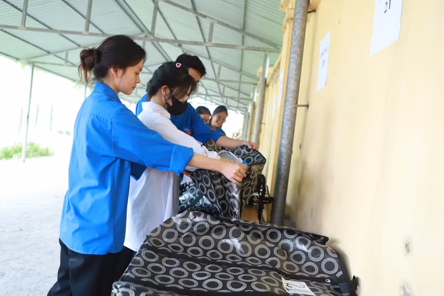 Lực lượng thanh niên tình nguyện hỗ trợ thí sinh gửi đồ ở khu vực cổng trường.