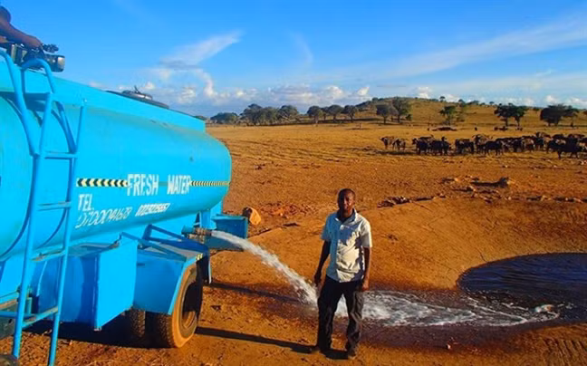 Người nông dân Patrick Kilonzo Mwalua đang chuyền nước từ xe bồn vào một hố bê-tông, trong Công viên quốc gia Tsavo West, Kenya. (Ảnh: This Is Africa).