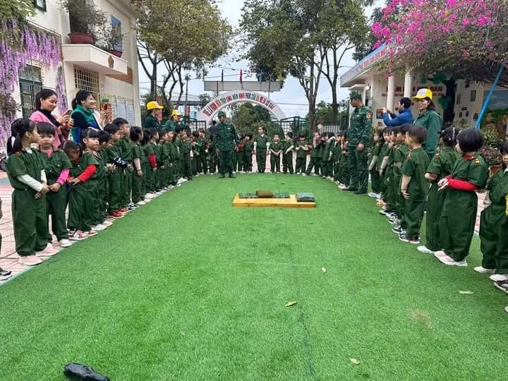 Các bé trải nghiệm làm chú bộ đội, thực hiện thao tác gấp chăn, màn.