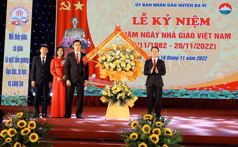 Ông Phùng Tân Nhị (phải) - Phó Bí thư thường trực Huyện ủy, Chủ tịch HĐND huyện Ba Vì thay mặt lãnh đạo huyện tặng hoa chúc mừng Phòng GD&ĐT Ba Vì.