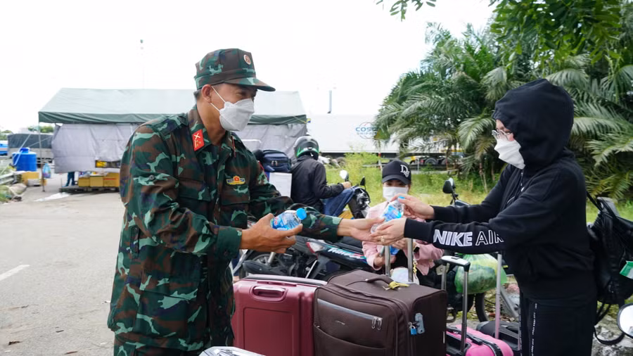 Các chiến sĩ công an và bộ đội hỗ trợ nước uống và thức ăn cho người dân tự phát về quê tại TP Cần Thơ.