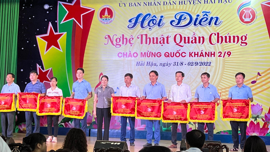 Ông Nguyễn Công Mẫn - Phó Chủ tịch UBND xã Hải Lý (bìa phải) và các đơn vị nhận cờ của UBND huyện Hải Hậu tiết mục văn nghệ xuất sắc.