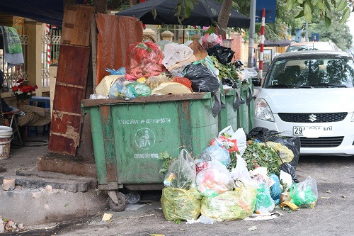 Đối diện phía bên kia đường nhiều xe rác chất cao không có biện pháp phủ bạt tạm thời bốc mùi hôi thối, ảnh hưởng tới môi trường khiến nhiều người dân bức xúc.