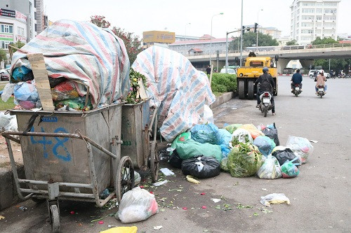 Tại chân cầu vượt Mai Dịch rác thải tràn xuống lòng đường ảnh hưởng tới các phương tiện tham gia giao thông.