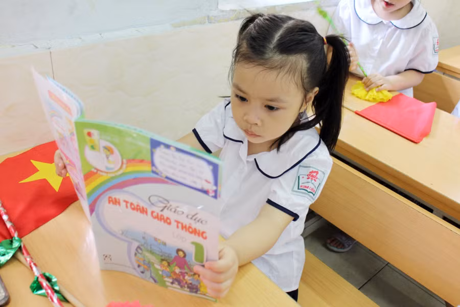 Bé chưa biết đọc tò mò với sách vở trên lớp sẽ được học ở buổi học đầu tiên của lớp 1