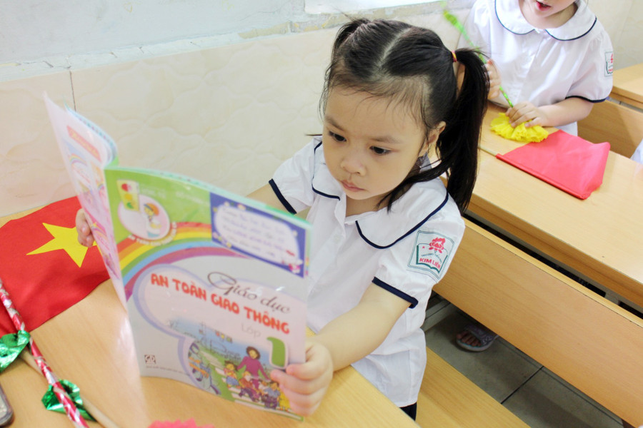 Bé chưa biết đọc tò mò với sách vở trên lớp sẽ được học ở buổi học đầu tiên của lớp 1