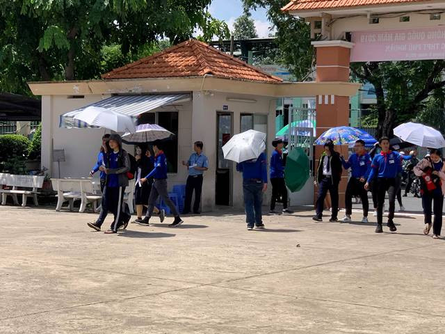 Ngoài cổng trường lực lượng sinh viên tình nguyện hoạt động hết công suất với việc che nắng cho từng bạn thí sinh
