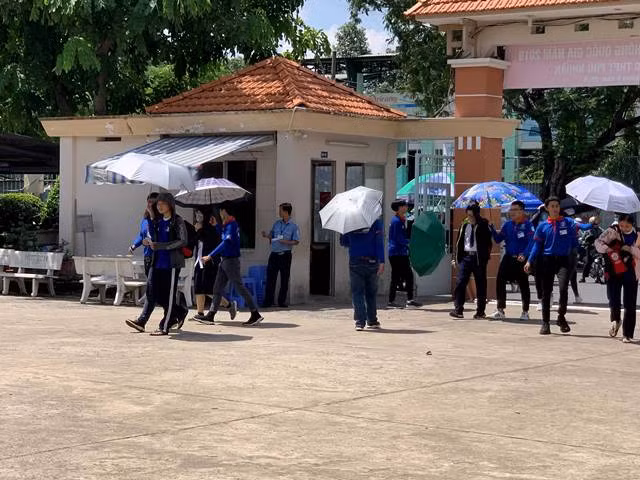 Ngoài cổng trường lực lượng sinh viên tình nguyện hoạt động hết công suất với việc che nắng cho từng bạn thí sinh
