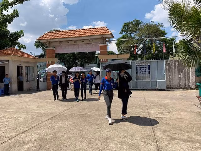 Lực lượng sinh viên tình nguyện của Trường ĐH Văn Hiến túc trực ngay tại cổng trường che nắng cho từng thí sinh