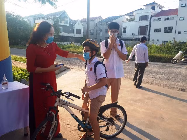 Giáo viên tại Trường Ischool kiểm tra thân nhiệt cho học sinh trước khi vào trường.