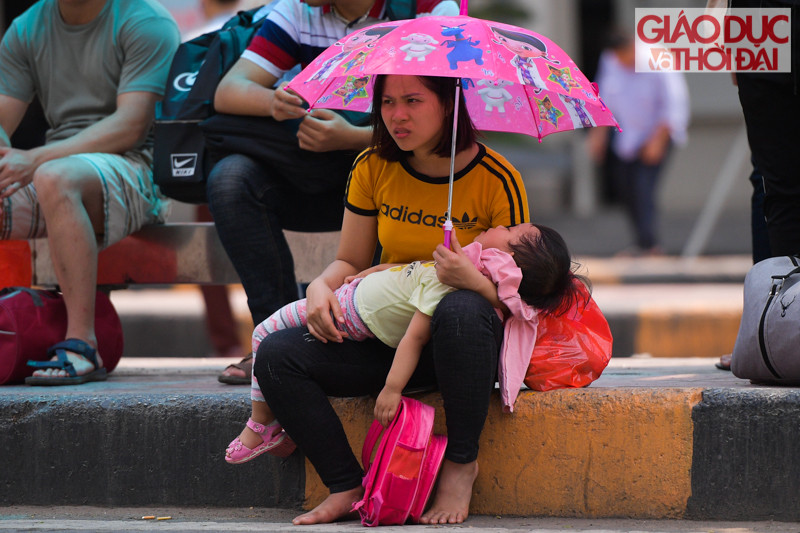 Thời tiết Hà Nộ oi bứ.c, rất nhiều hành khách phải dùng ô, áo trống nắng hay thậm chí là những tờ báo để che, quạt