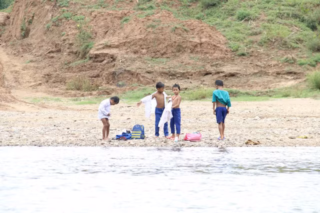 Nhóm học sinh mặc lại quần áo sau khi lội sông