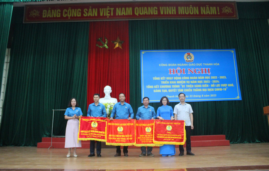 Ông Tạ Hồng Lựu - Phó Giám đốc Sở GD&amp;ĐT Thanh Hóa; bà Trịnh Thị Hoa - Phó Chủ tịch Thường trực Liên đoàn Lao động tỉnh Thanh Hóa trao Cờ thi đua cho các đơn vị xuất sắc. Ảnh: LT.