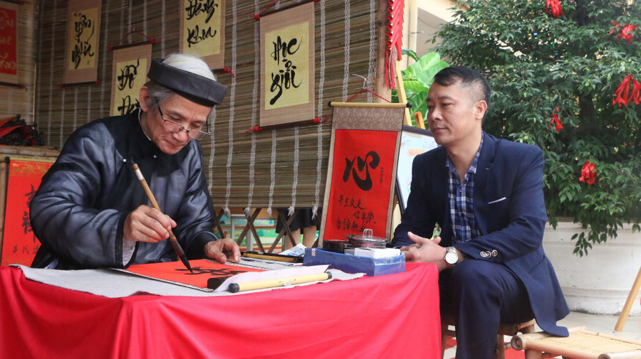 Anh Phạm Đức Việt bên bàn cho chữ của ông Đồ.