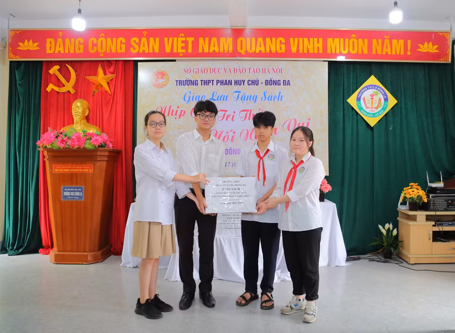 Các em học sinh Trường THPT Phan Huy Chú - Đống Đa (trái) trao tặng sách cho đại diện học sinh Trường THCS Đông La (Hoài Đức, Hà Nội).