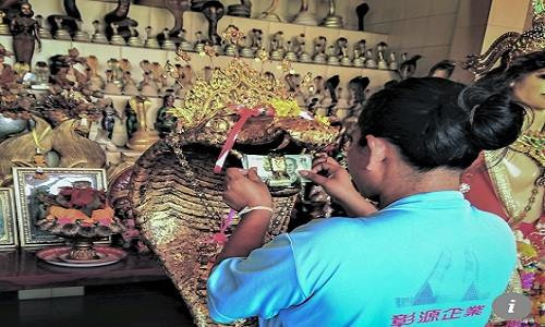 Nhiều người còn nhét cả tiền giấy vào miệng tượng rắn để chắc chắn mong ước của mình thành hiện thực. Nhiều người còn nhét cả tiền giấy vào miệng tượng rắn để chắc chắn mong ước của mình thành hiện thực. Ảnh: SCMP.