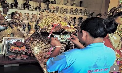 Nhiều người còn nhét cả tiền giấy vào miệng tượng rắn để chắc chắn mong ước của mình thành hiện thực. Ảnh: SCMP.