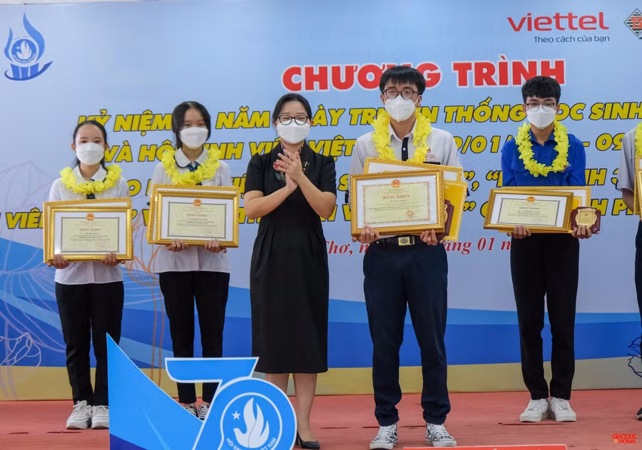 Bà Trần Vĩnh Nghi, Trưởng Ban Dân vận Thành ủy trao Bằng khen của Bộ trưởng Bộ Giáo dục và Đào tạo cho em Phạm Vũ Thắng.