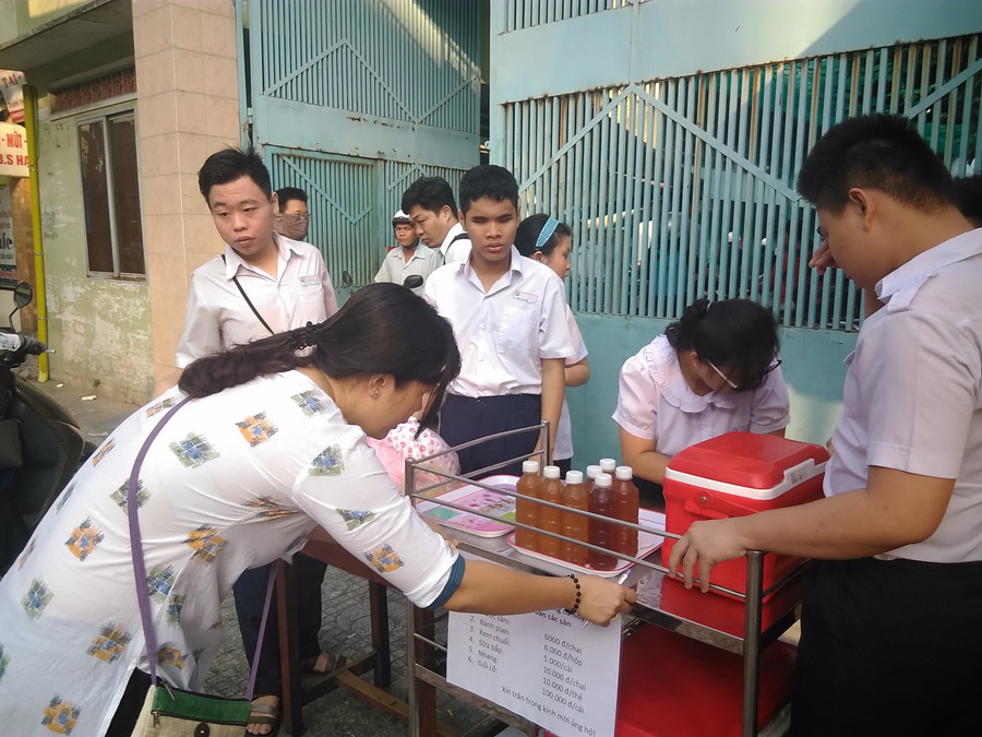 Cô và trò cùng sắp xếp lại kệ hàng và treo lại bảng niêm yết giá các mặt hàng gồm: Nước sâm: 6.000đ/ chai; bánh plan: 6.000đ/hộp; kem chuối 5.000đ/cái; sữa bắp: 10.000đ/chai; nhang: 10.000đ/thẻ; gối cổ: 100.000đ/cái…