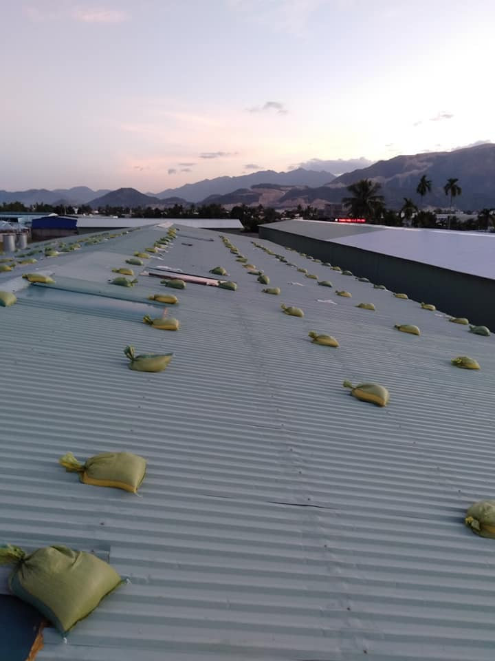 người dân chèn bao cát trên mái tôn để chống bão