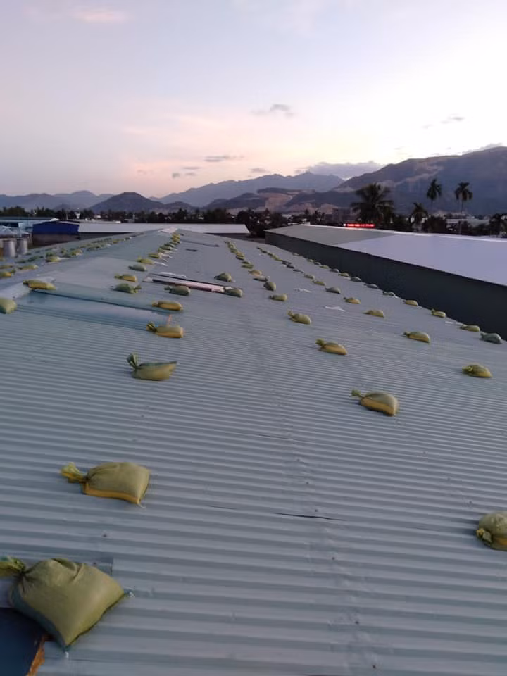 người dân chèn bao cát trên mái tôn để chống bão