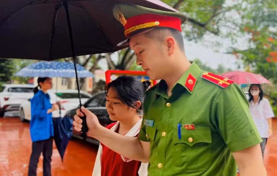 Lực lượng công an có mặt tại các điểm thi hỗ trợ thí sinh trong cơn mưa nặng hạt. (Ảnh: CATH).