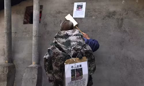 Ông chăm chút từng tờ rơi dán lên tường. Chỗ nào giấy bị rách hay quá cũ, ông sẽ thay ngay tờ mới. Ảnh: Beijing News.