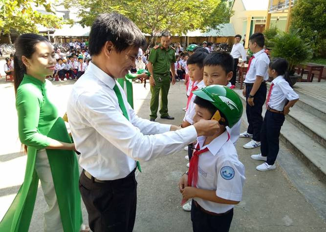 Ông Nguyễn Thành Nhân đại diện lãnh đạo Công ty MTV Mai Linh trao tặng mũ bảo hiểm cho học sinh. Ảnh: Mỹ Liên