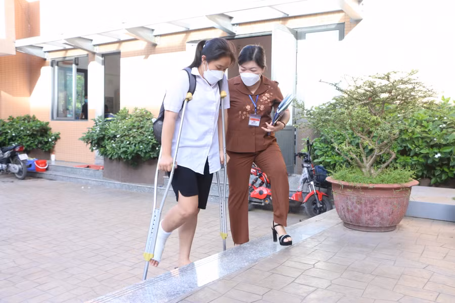 Tại điểm thi Trường THCS Tân Mai có 1 thí sinh bị đau chân được lãnh đạo quận động viên, hỗ trợ đưa lên tận phòng thi.