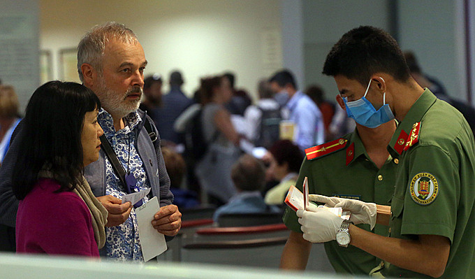 KIểm soát viên nhập cảnh cửa khẩu Nội Bài đeo găng tay, khẩu trang, khi hướng dẫn, làm việc, tiếp xúc với người nước ngoài hôm 11/3. Ảnh: Bá Đô