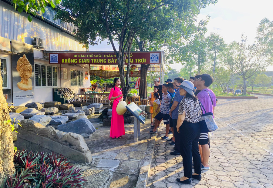 Du khách được hướng dẫn viên giới thiệu về khu trưng bày hiện vật ngoài trời tại di sản Thành nhà Hồ.