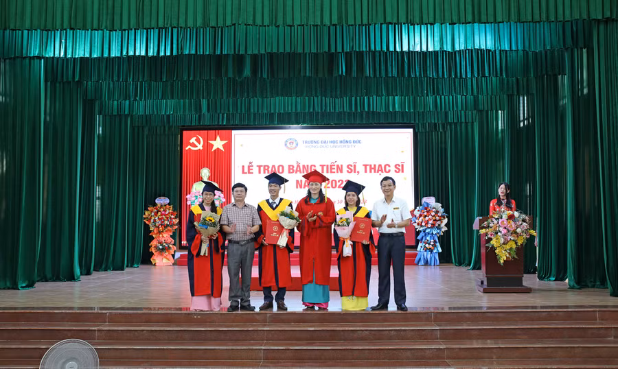 Đại diện ban lãnh đạo nhà trường trao bằng tốt nghiệp cho các tân tiến sĩ. 