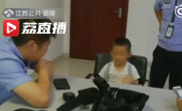 Kaikai ở đồn cảnh sát chờ bố tới đón. Kaikai ở đồn cảnh sát chờ bố tới đón. Ảnh: Jiangsu TV.