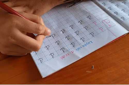 Một em học sinh có đôi tay bị tật nguyền nên viết chữ gặp khó khăn. Ảnh: Đắc Thành.