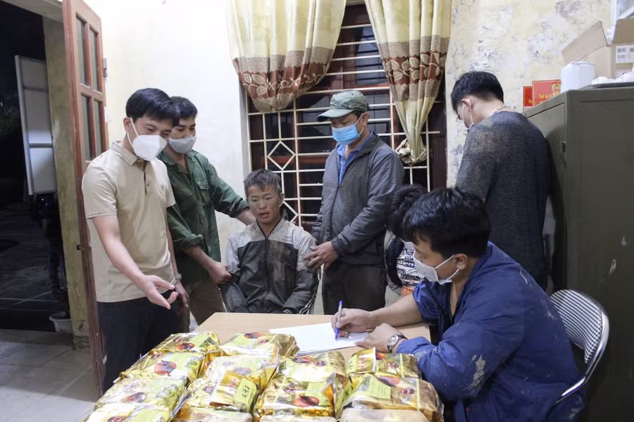 Hai đối tượng (ngồi giữa) cùng tang vật tại cơ quan Công an.