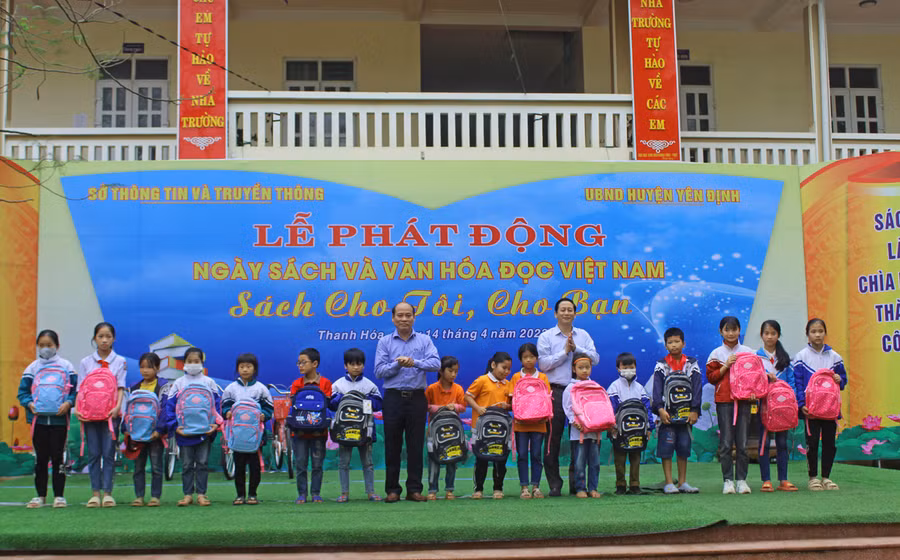 Ông Lê Văn Nam - Phó Giám đốc Sở Thông tin và Truyền thông, ông Hoàng Trung Hưng - Trưởng ban Tuyên giáo Huyện ủy trao quà của nhà tài trợ cho học sinh. Ảnh: LT.