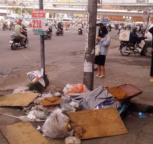 Khách đứng đợi xe buýt phải tránh ra chỗ khác vì điểm dừng đỗ chất đầy rác