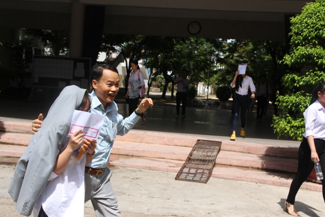 Vừa bước ra khỏi phòng thi, người cha vội cởi chiếc áo, khoác lên vai con mình che nắng.