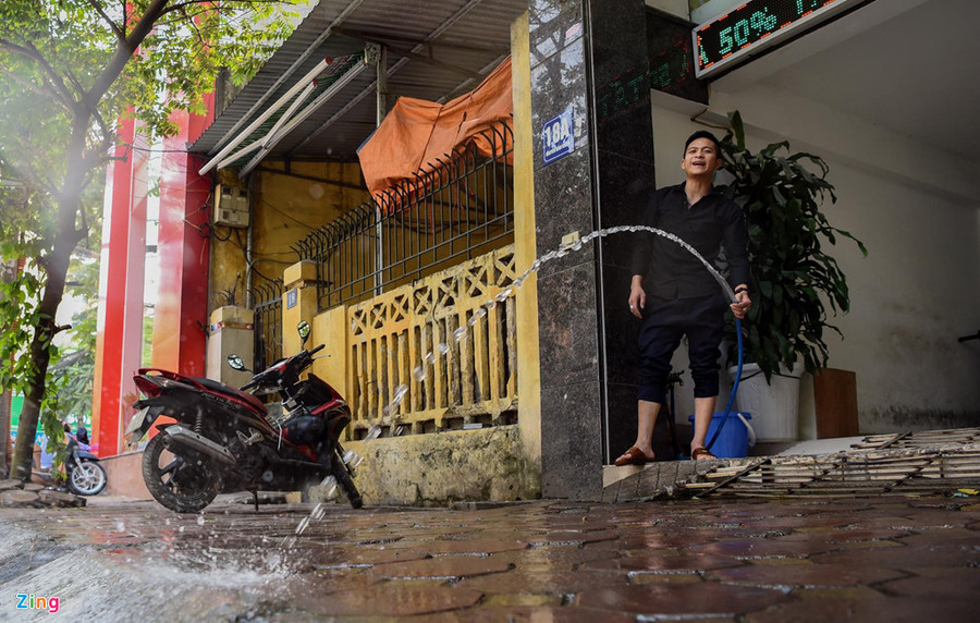 Người dân xịt nước lên vỉa hè trước cửa nhà làm giảm không khí oi bức. Người đàn ông này nói việc xịt nước có thể giúp hạ từ 4 tới 5 độ C. Mat duong o Ha Noi nong hon 50 do C hinh anh 7